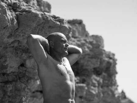 beautiful strong young man standing at the cliff and looking into the distanceの写真素材