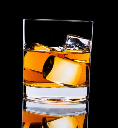 Photo of a glass of whiskey and ice on a black backgroundの写真素材
