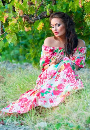 Beautiful woman in a bright dress near the vineyardの写真素材
