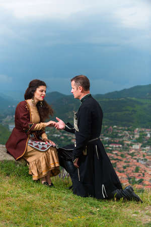 Man and woman in Georgian national dress on a background of mountains