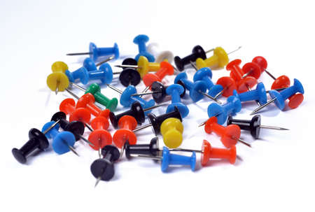 Thumbtacks of different colors lie on a white backgroundの写真素材