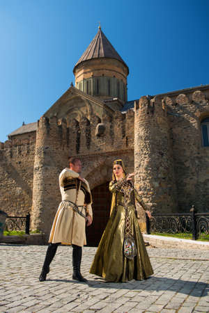 A man and a woman in Georgian national clothes outdoors on a background of an old buildingの写真素材