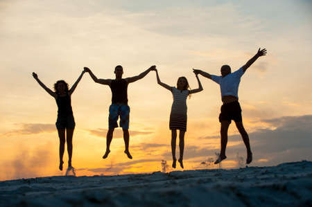 silhouette people jumping at sunsetの写真素材