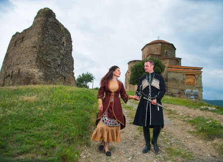 Man and woman in Georgian national dress on a background of mountains