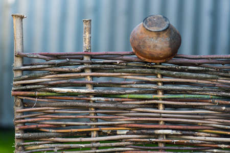 An old jug hanging on a wooden fence in natureの写真素材