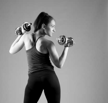 Girl with dumbbells in sport uniform during training.の写真素材