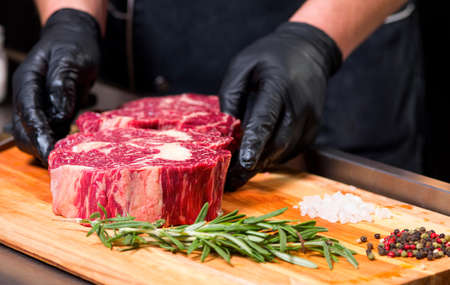 The cook prepares meat steak on the kitchen table.