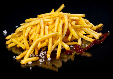 French fries with sauce on a black background.