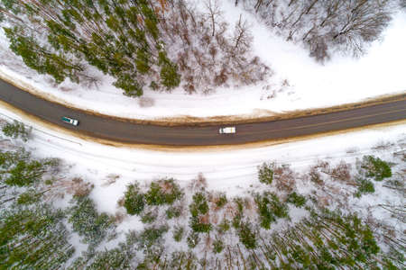 A car on the track and a forest in winter aerial view.の写真素材