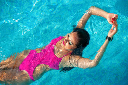 Sexy girl in a pink swimsuit in the pool.