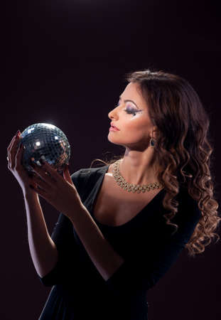 Girl with curly hair holds a shiny ball in her hands.の写真素材