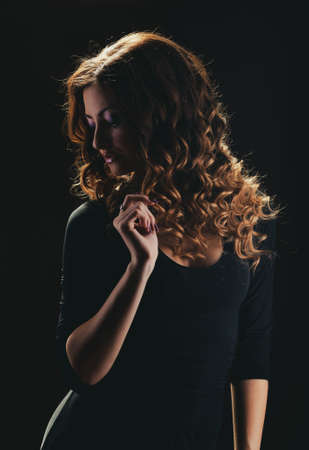 Beautiful curly girl on a dark background.の写真素材
