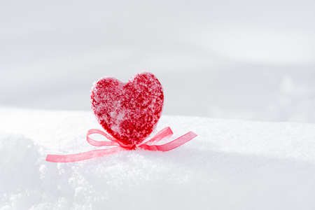 Red heart with a bow in the snow.の写真素材