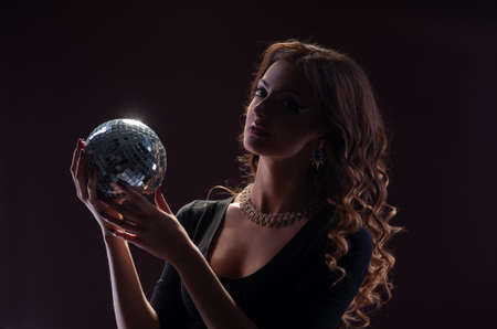 Beautiful woman with a shiny ball on a dark background.の写真素材