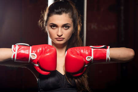 Young woman in boxing gloves on a dark background.の写真素材