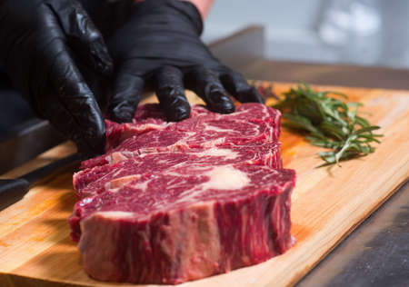 Beef meat in chunks on the board and human hands.の写真素材