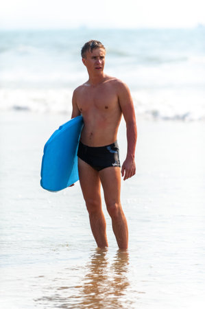 Young man with a board on the seashore.の写真素材