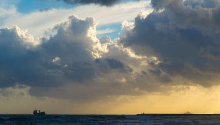 Dark sky with rays of sunlight and a ship at sea.