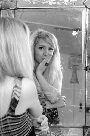 blonde woman analyzing beauty in mirrrorの写真素材