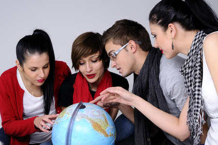 four teens searching on globe travel destinationsの写真素材