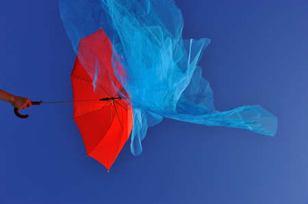 human hand holding flying red umbrellaの写真素材