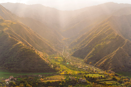 landscape of mountain range with green slopes and bushes in golden sunset rays and a green valley belowの写真素材