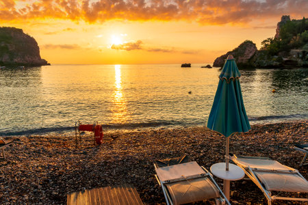 morning or evening landscape with nice beach with deck chairs and umbrellas during sunrise or sunset with amazing sea with rocks and beautiful clouds on backgroundの写真素材