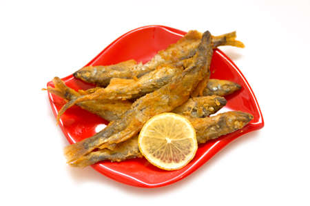 Fried fish and lemon on a red plate