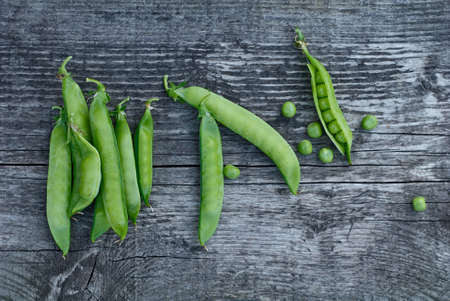 Green pea pods beautifully lie on vintage wooden surfaces, top viewの写真素材