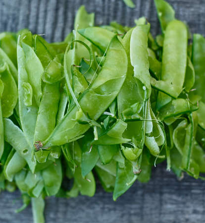 Bunch of opened pods from eating green peas lying on wooden surface