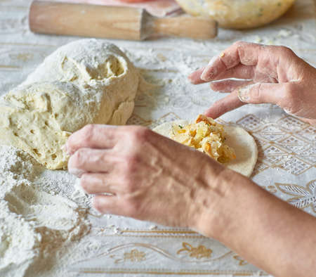 Kitchen, cooking pies with dough on the table, close upの写真素材