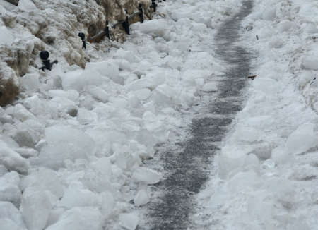 Winter path on the iced over pavement among the ice chunksの写真素材