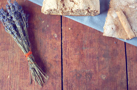 Vintage wooden background with homemade bread and bunch of dry lavender from above