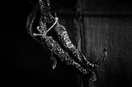 Bunch of dry peppers on dark fabric background close up in low key