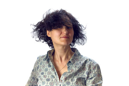 Young woman with black curly waving in the wind hair looks at the camera close up