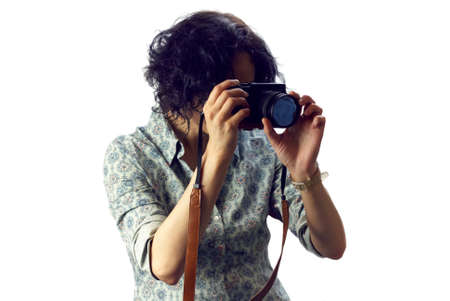 Young woman with black curly hair holding camera in hand and making photos