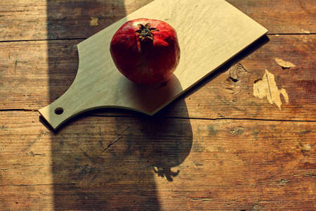 Pomegranate on old rustic table in evening lighting with shadowの写真素材