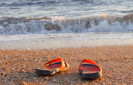 Water's edge at sea coast and beach flip flops closeup