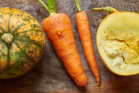 Pumpkins and carrots on rustic wooden background closeup from aboveの写真素材