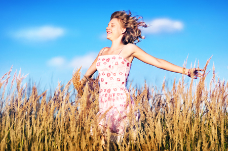 Beautiful young girl running through the high grassの写真素材