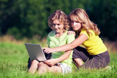Happy girl on green grass with laptopの写真素材