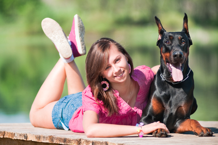 Young beautiful girl with a dog near lakeの写真素材