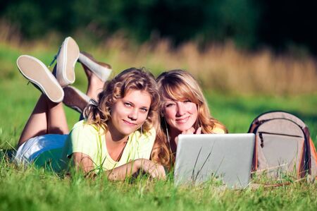 Happy girl on green grass with laptopの写真素材