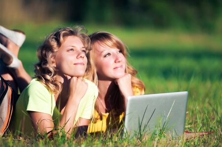 Happy girl lie on green grass with laptopの写真素材