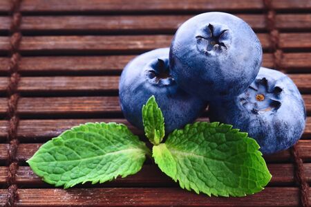 Fresh blueberry with green leafs of mint on wooden backgroundの写真素材