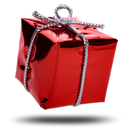 Red gift with a silver ribbon and a bow falling on white backgroundの写真素材