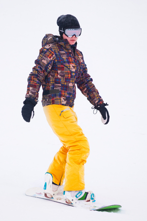 Young girl snowboarder in yellow pants on the boardの写真素材