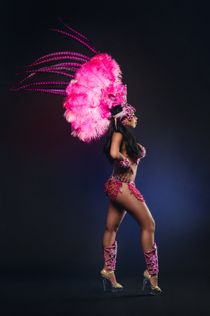 Cute young girl in bright colorful carnival costume on dark backgroundの写真素材