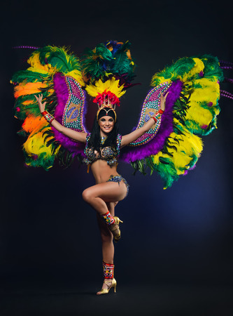 Cute young girl in bright colorful carnival costume on dark backgroundの写真素材