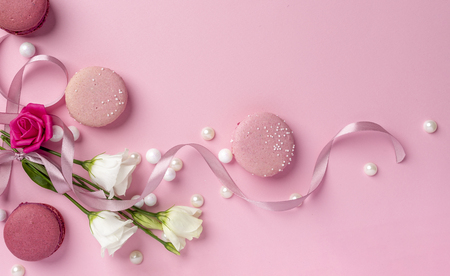 White rose bouquet with red and pink macaroons and pearls on a clear flat pink backgroundの写真素材